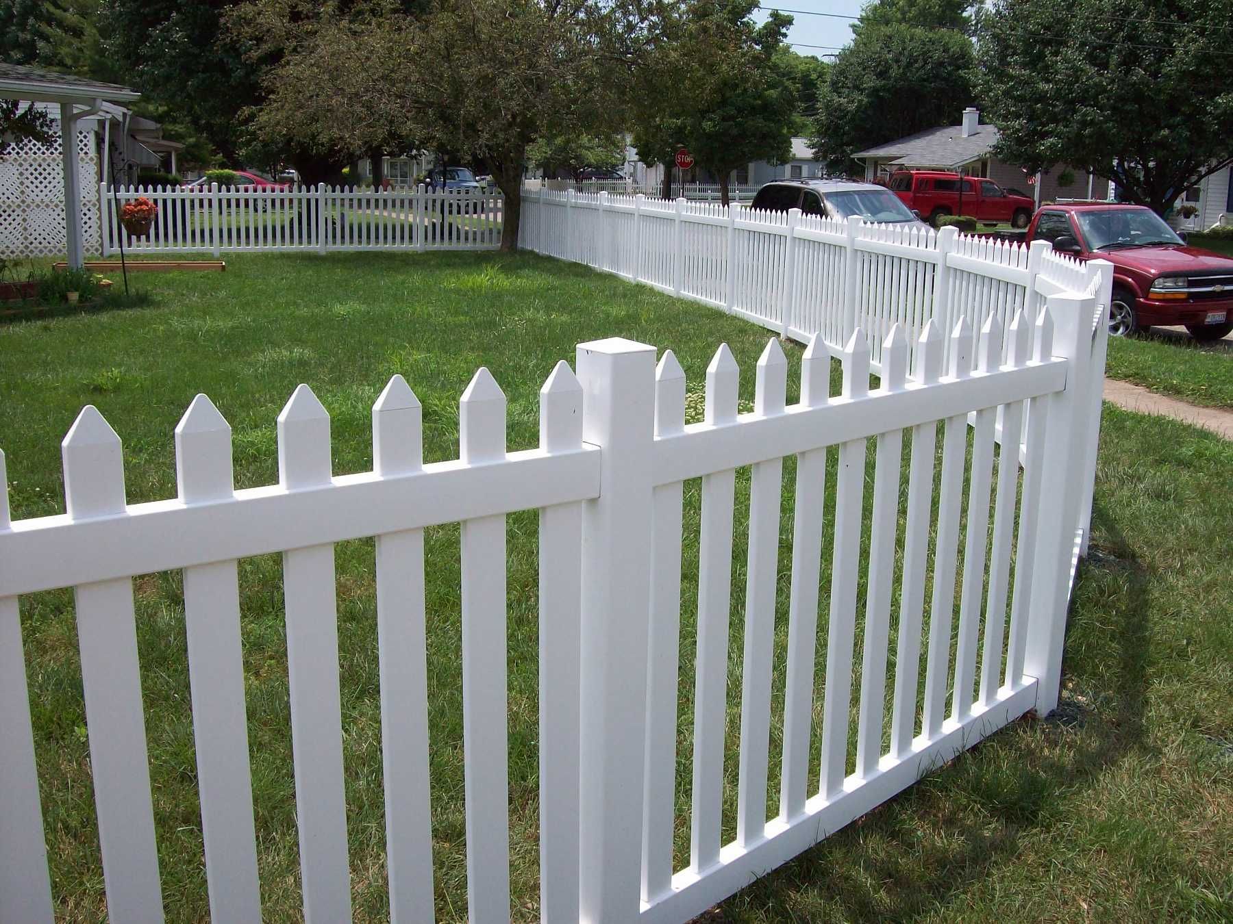 A white picket fence surrounds a lush green yard