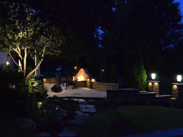 A patio area with a fireplace and trees lit up at night.