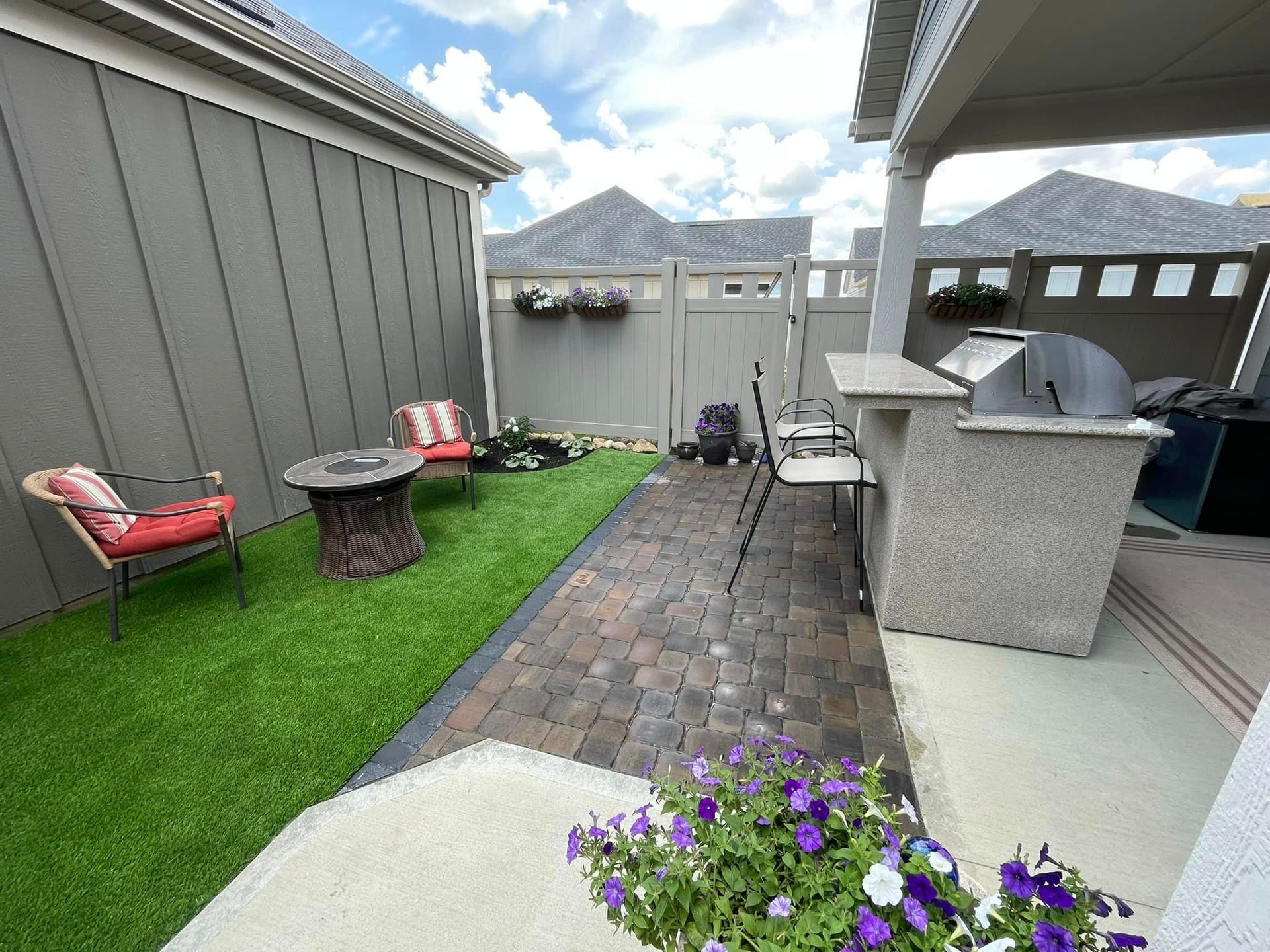 A backyard with a fire pit , chairs , and a grill.