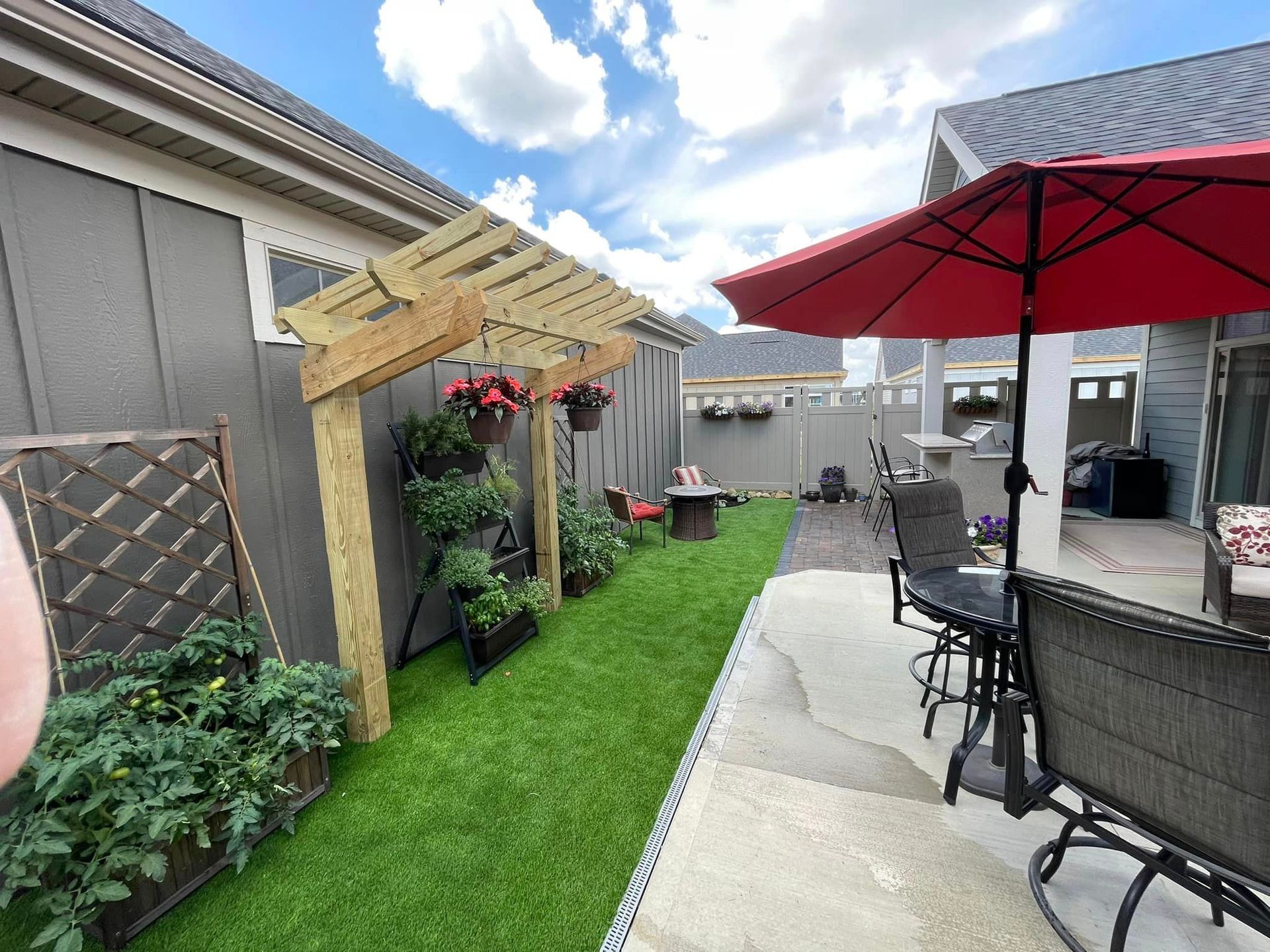 A backyard with a pergola , chairs , and umbrellas.