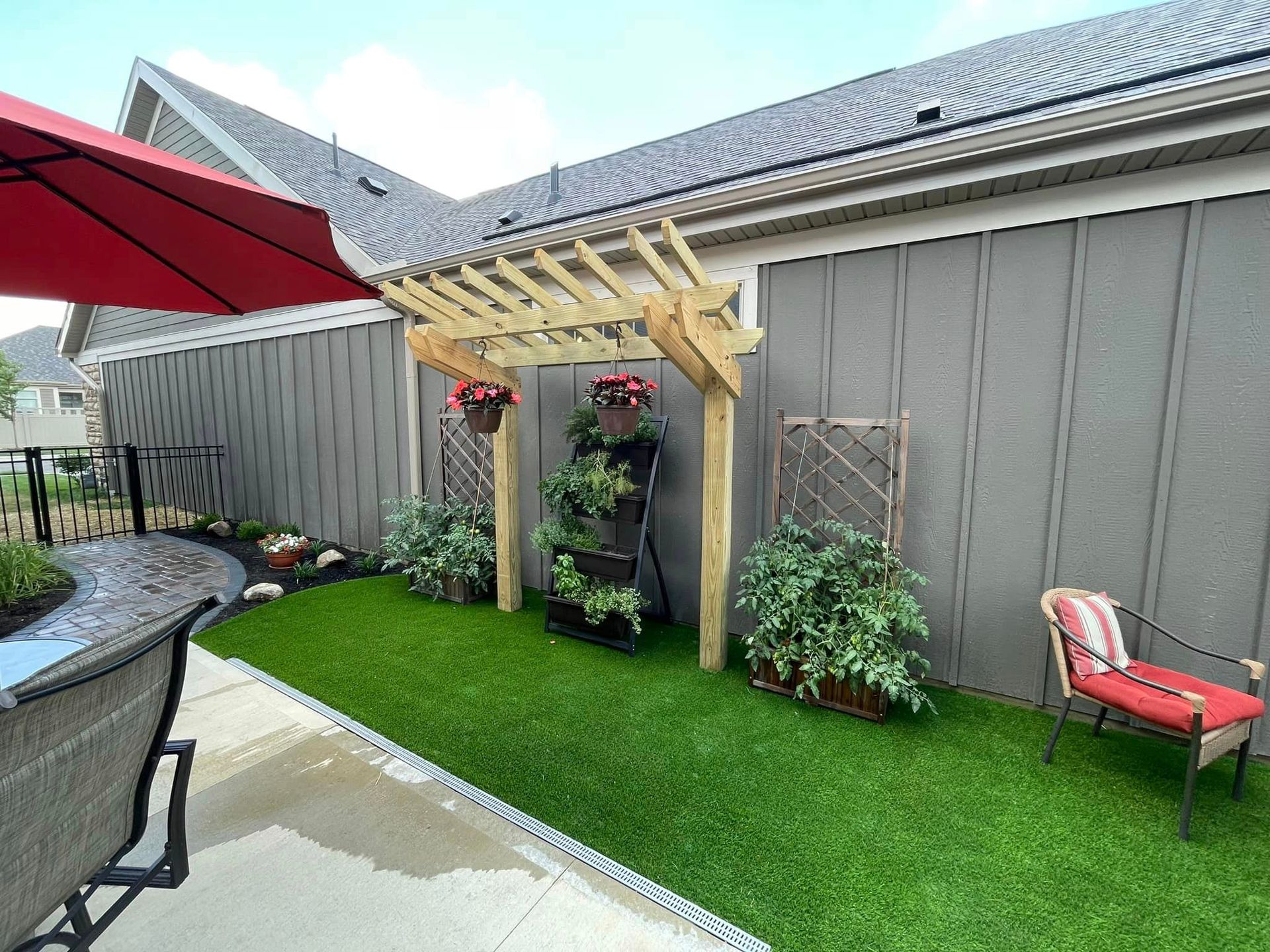 A backyard with a pergola , chairs , and umbrellas.