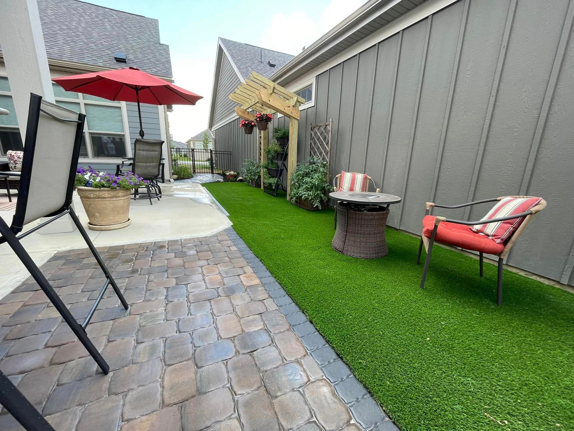 A patio with chairs , umbrellas and a fire pit.