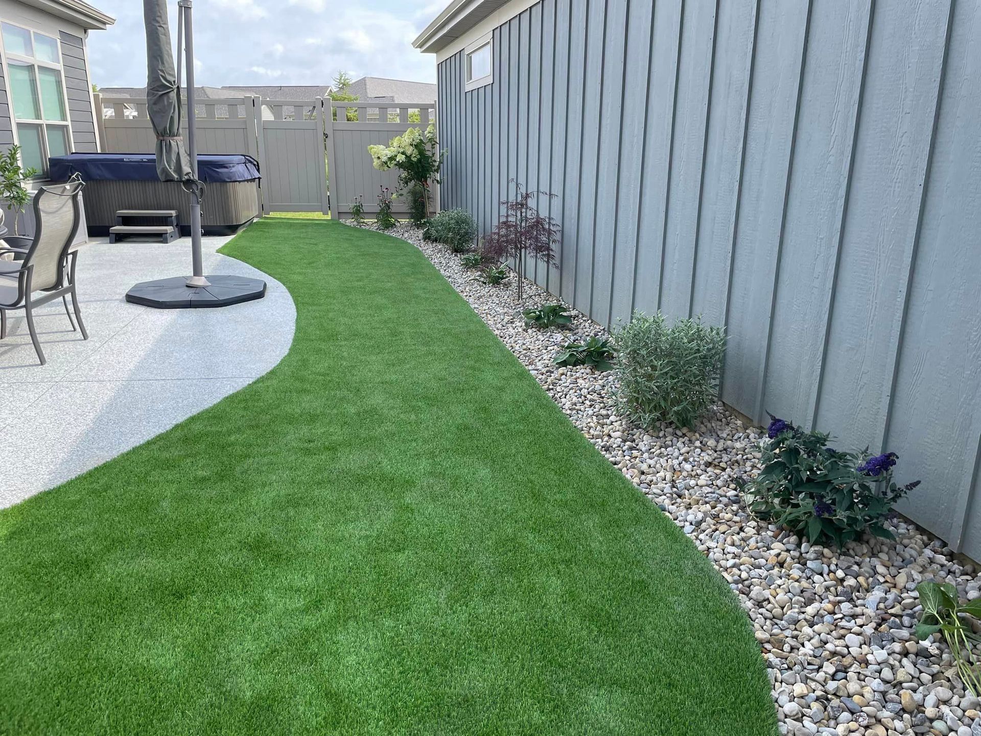 A backyard with a fence , a patio , and a hot tub.