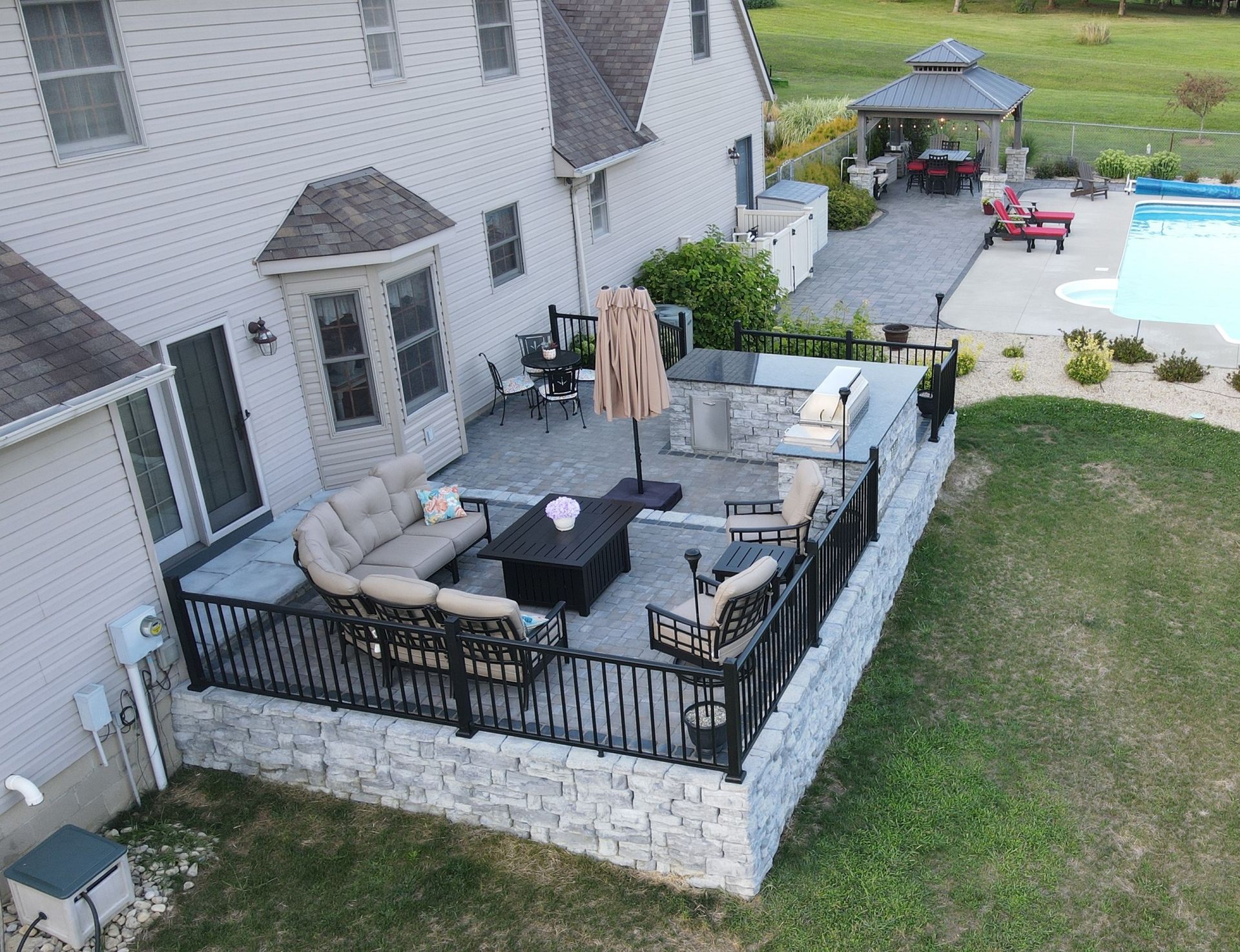 An aerial view of a backyard with a patio and a swimming pool.