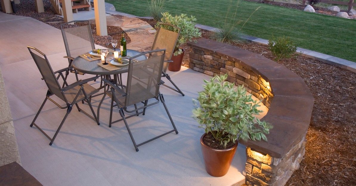 A patio with a table and chairs and potted plants.