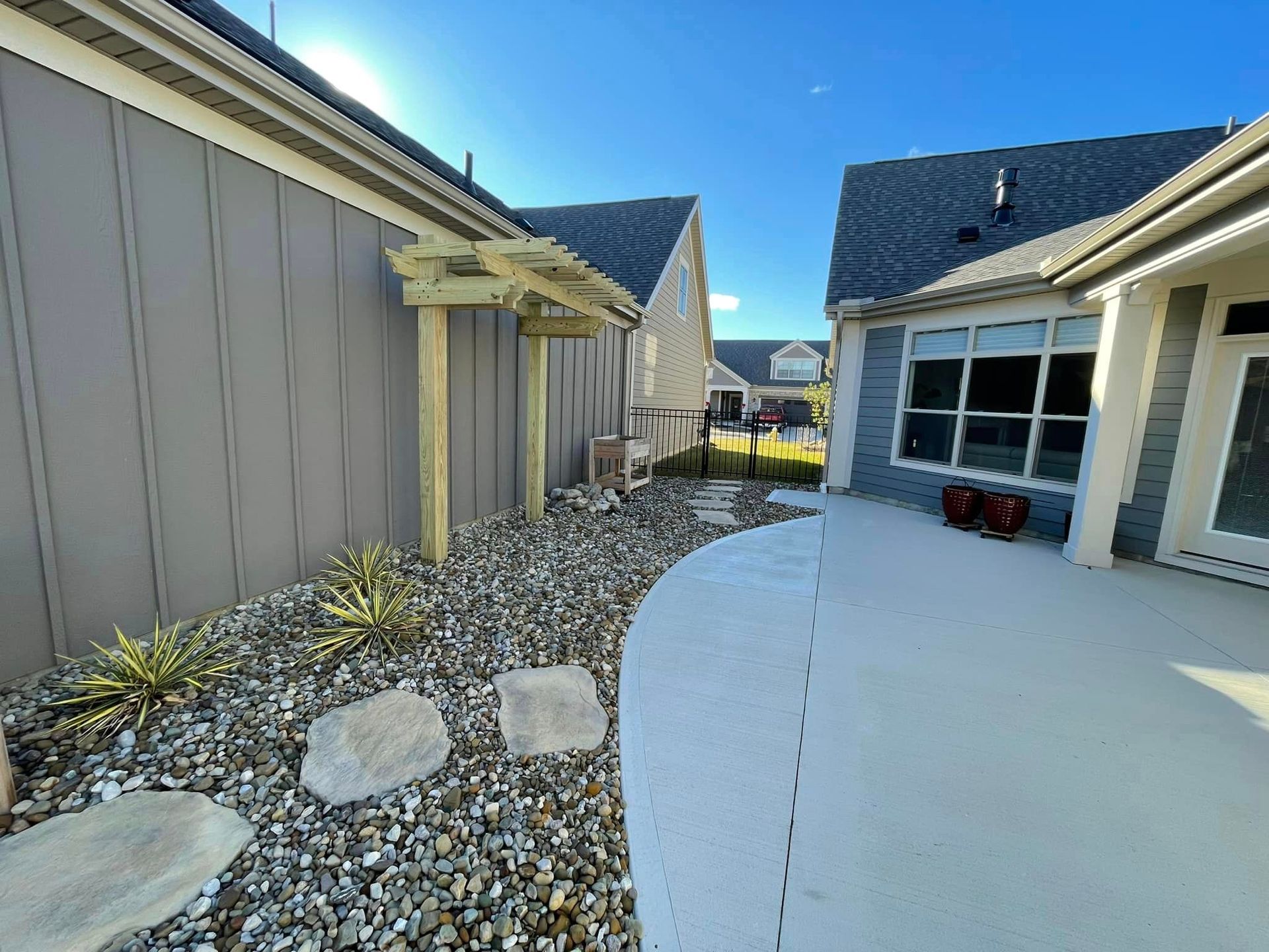 A patio area with a pergola and rocks in front of a house.