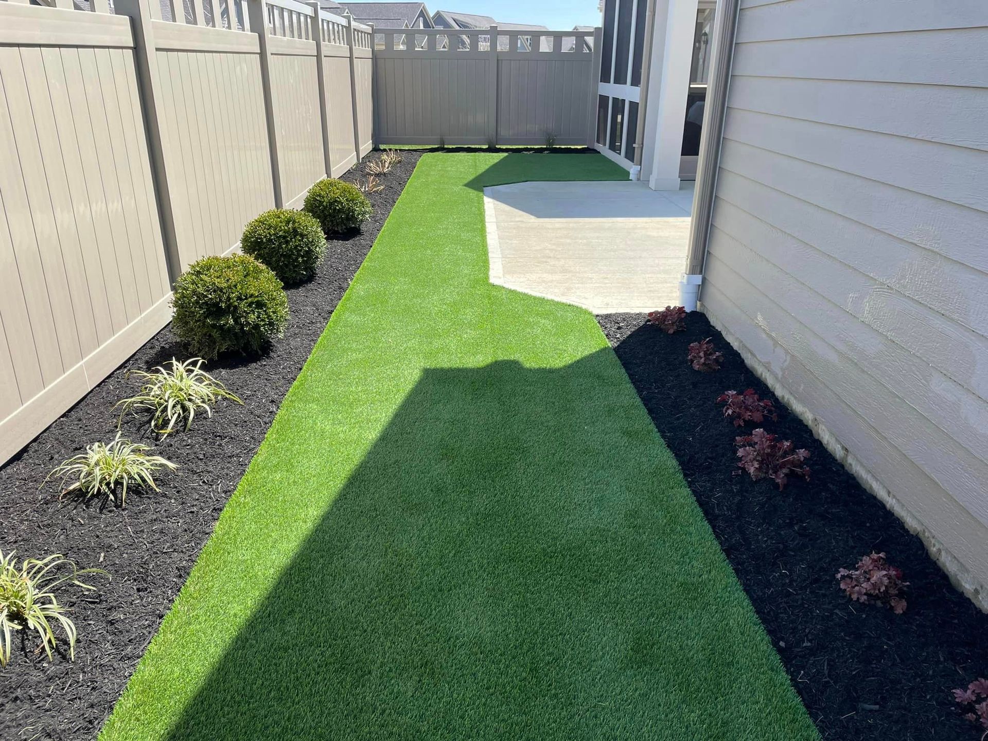 A backyard with a fence and a lush green lawn.