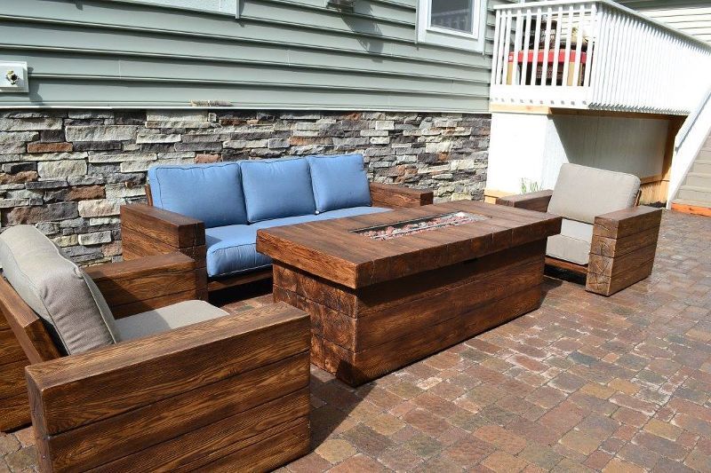 A patio with a couch , chairs , and a fire pit.
