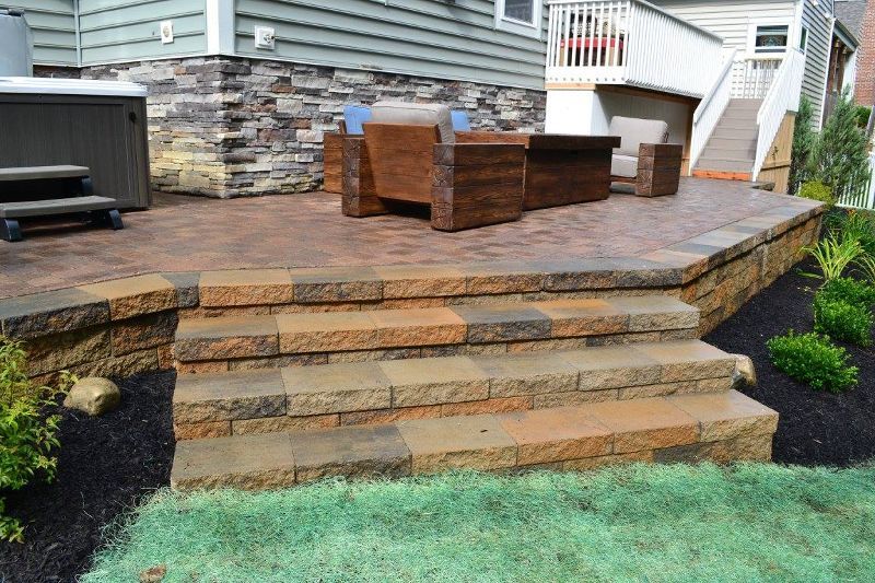 A patio with stairs leading up to it and a hot tub in the background.