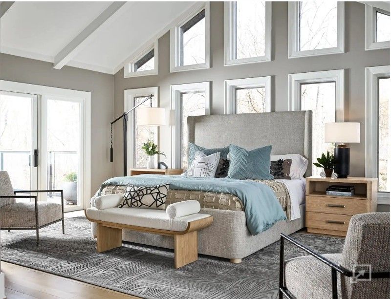 A bedroom with a bed , chairs , nightstands and a bench.