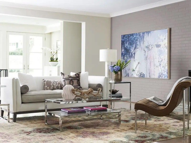 A living room with a couch , chair , coffee table and painting on the wall.
