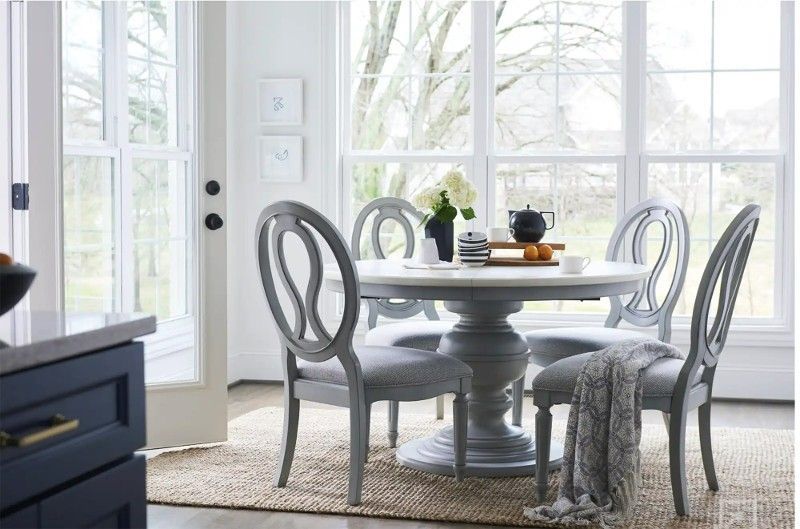 A dining room with a table and chairs in front of a large window.