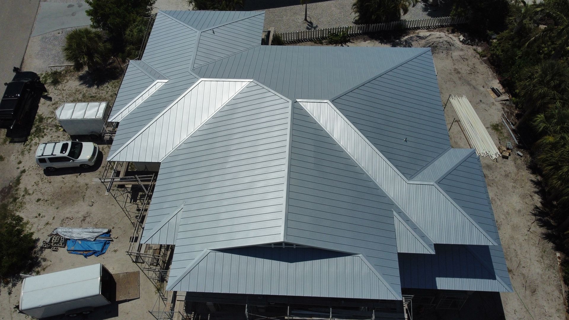 Overhead view of a house under construction with a reflective, metallic roof.
