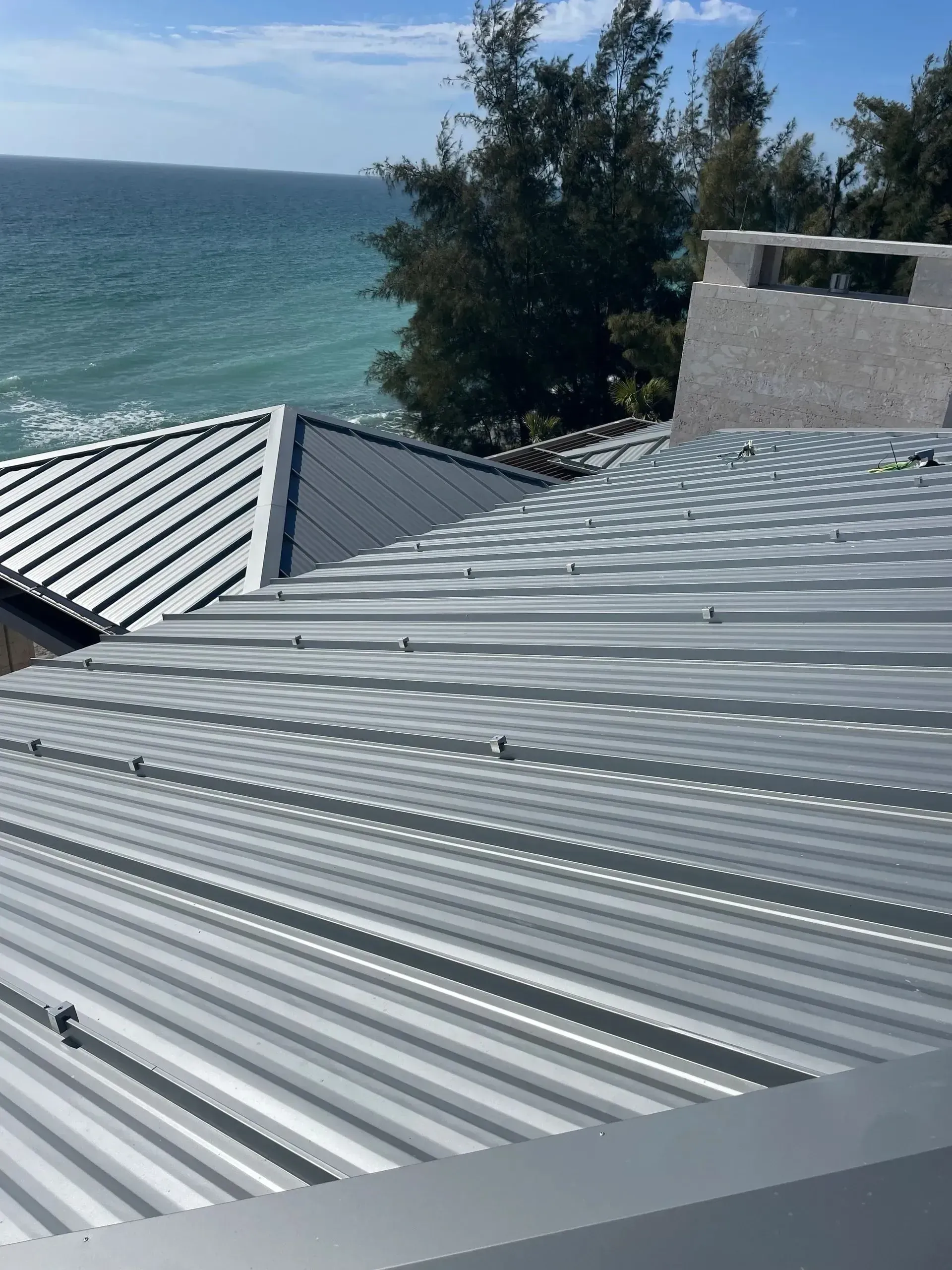 Metal roof with ocean view. The roof is silver with several small vents, and the ocean is blue.