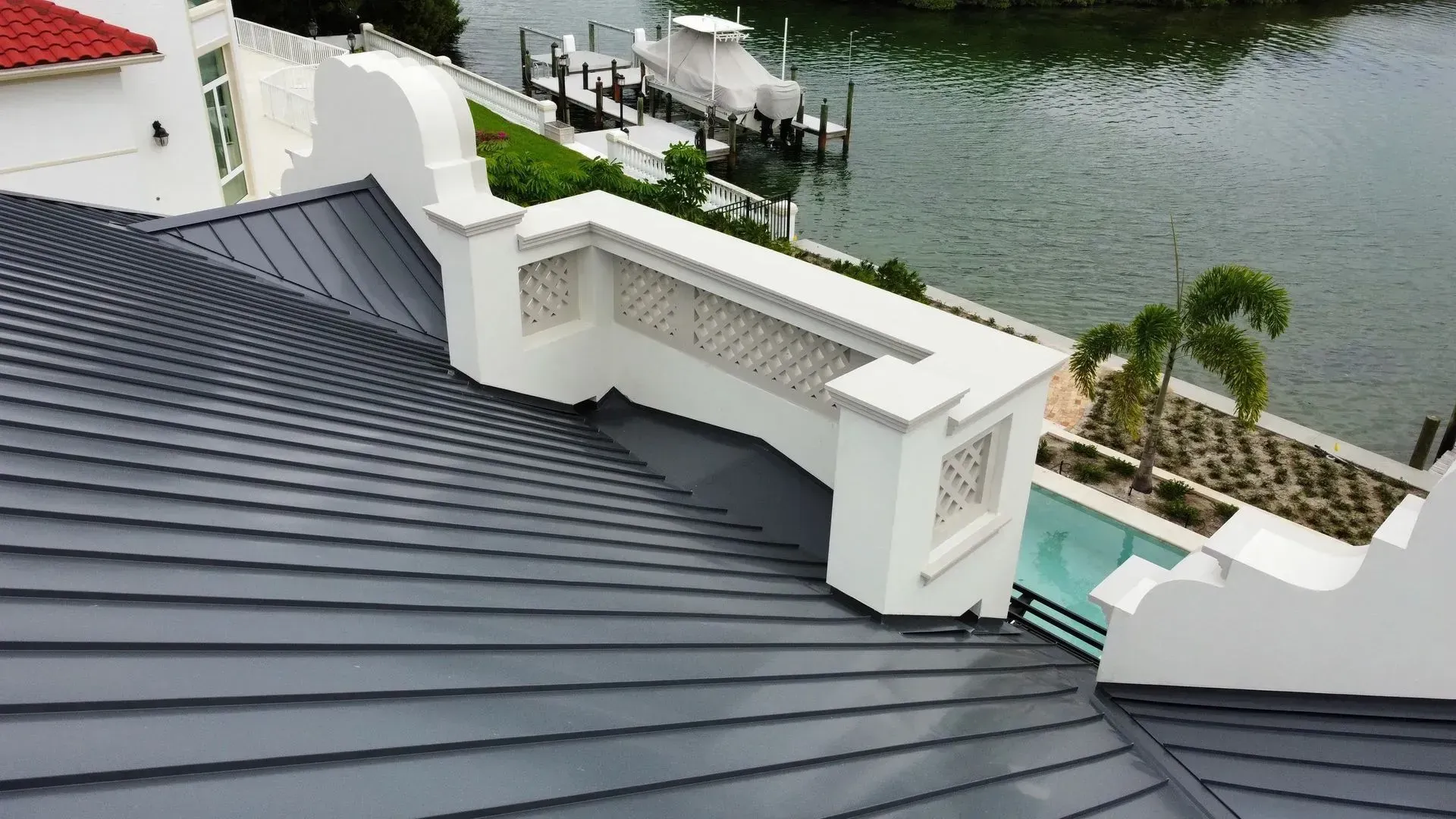 Gray metal roof with white trim overlooking a body of water and a dock.