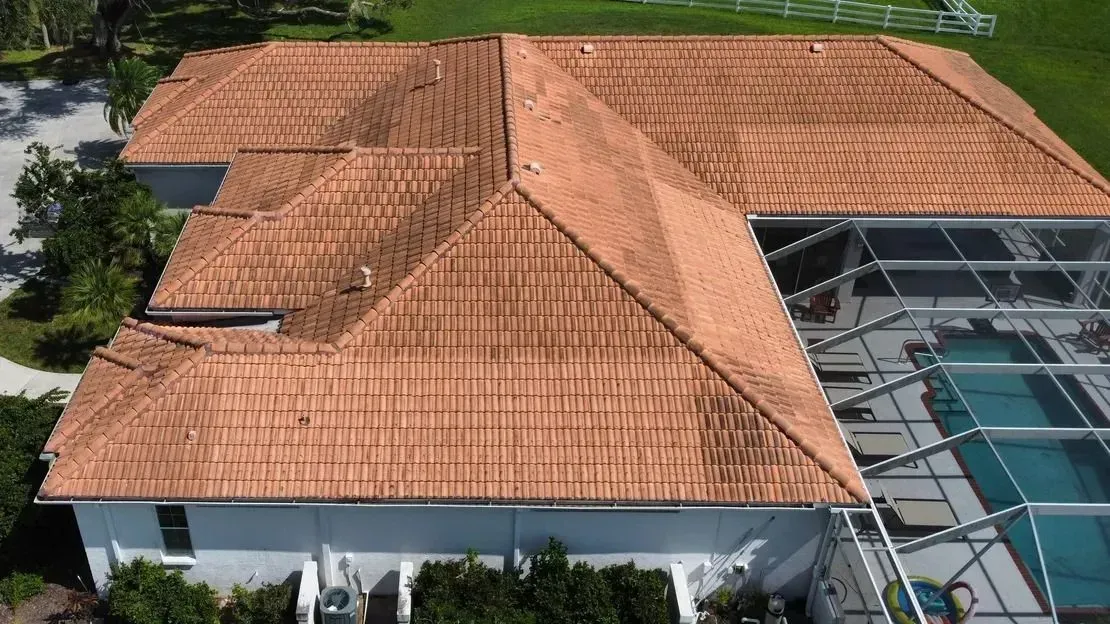 Orange tile roof on a white house, pool with screen enclosure visible.