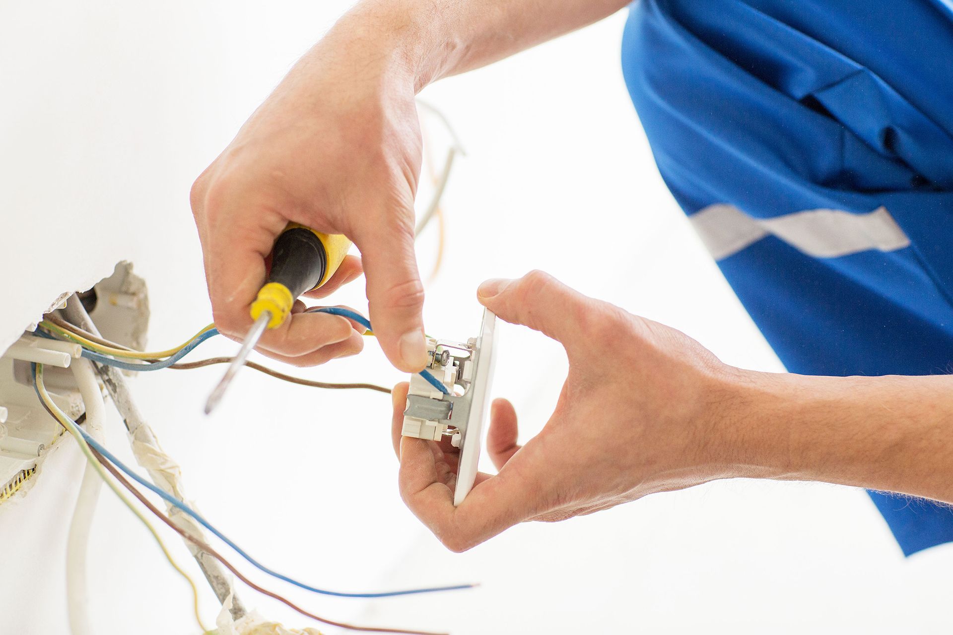 Close up of electrician's hands with screwdriver fixing socket