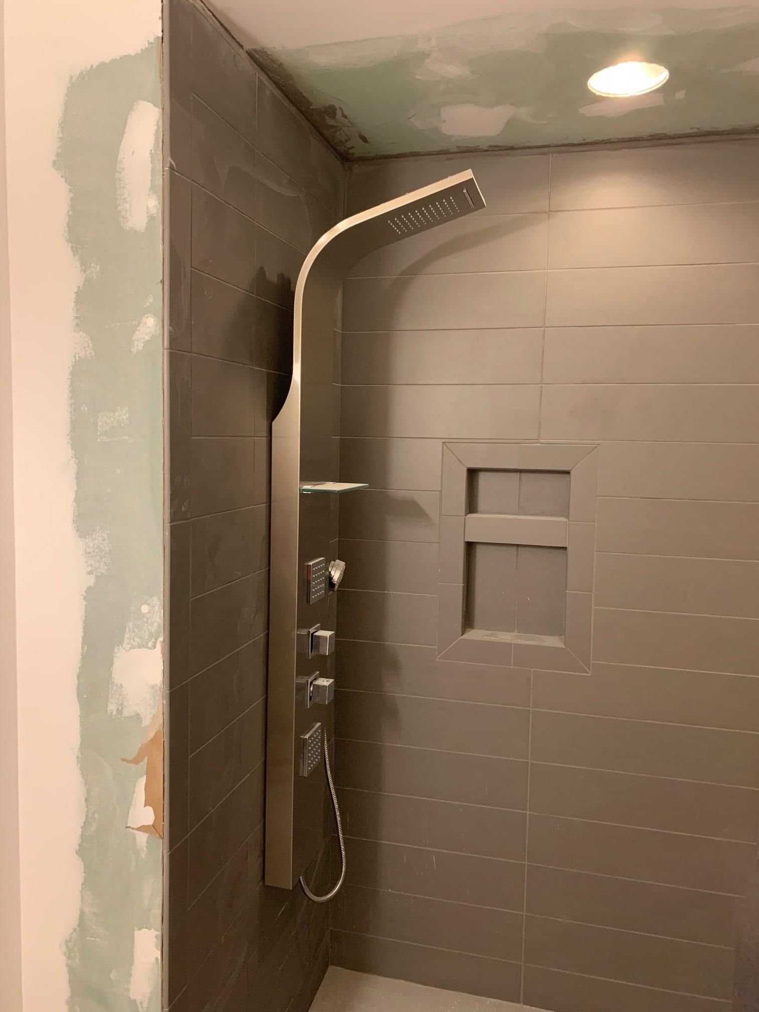 Shower with a shower head and a shelf in the wall