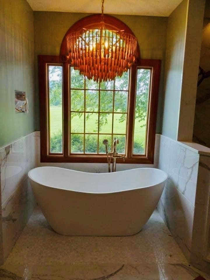 A bathroom with a bathtub and a chandelier hanging from the ceiling