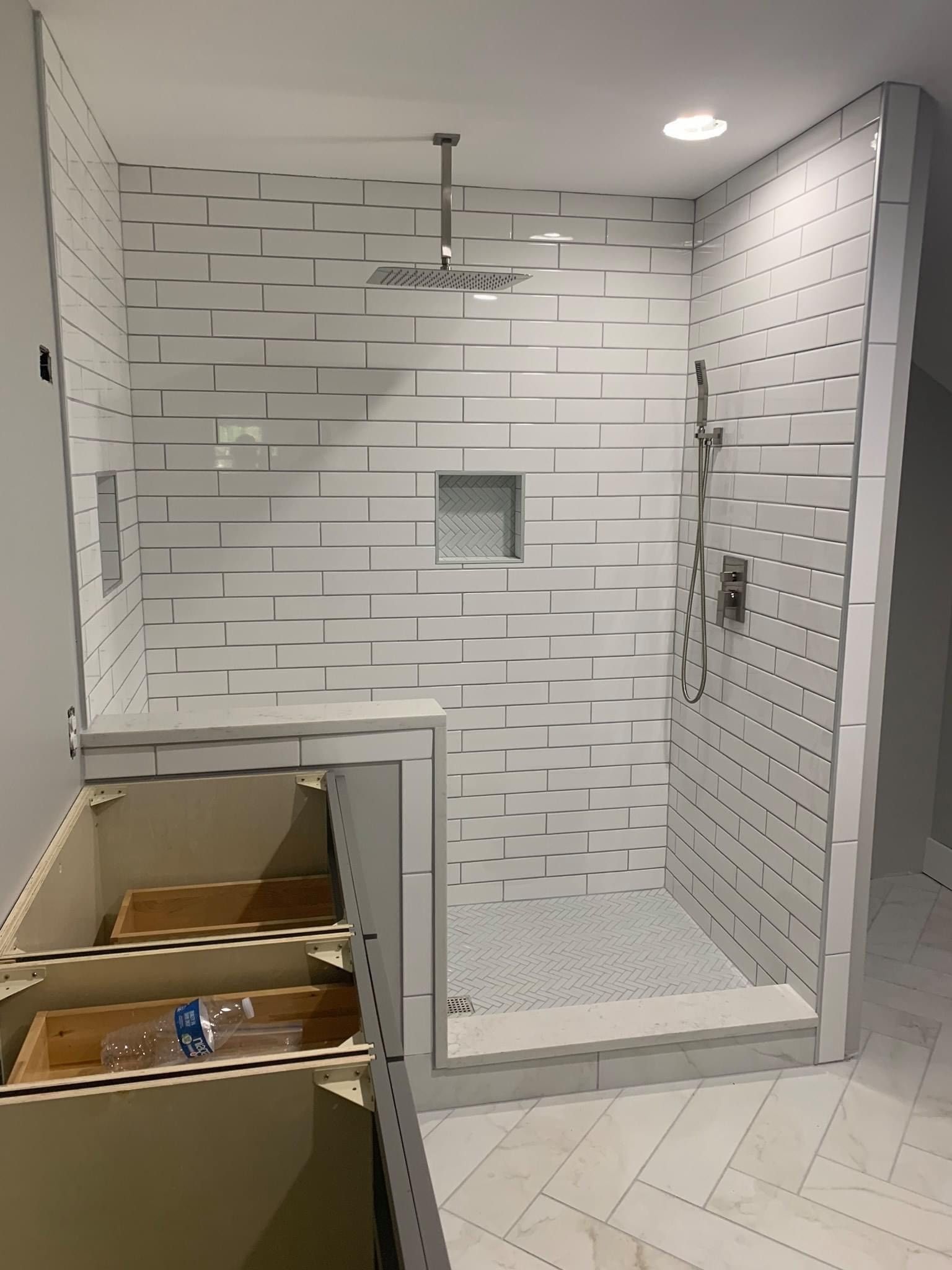 A bathroom with white tiles and a walk in shower