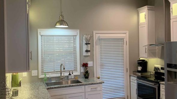 A kitchen with white cabinets, a sink, a refrigerator, and a window