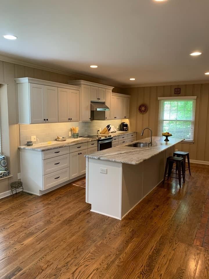 A kitchen with white cabinets and hardwood floors and a large island