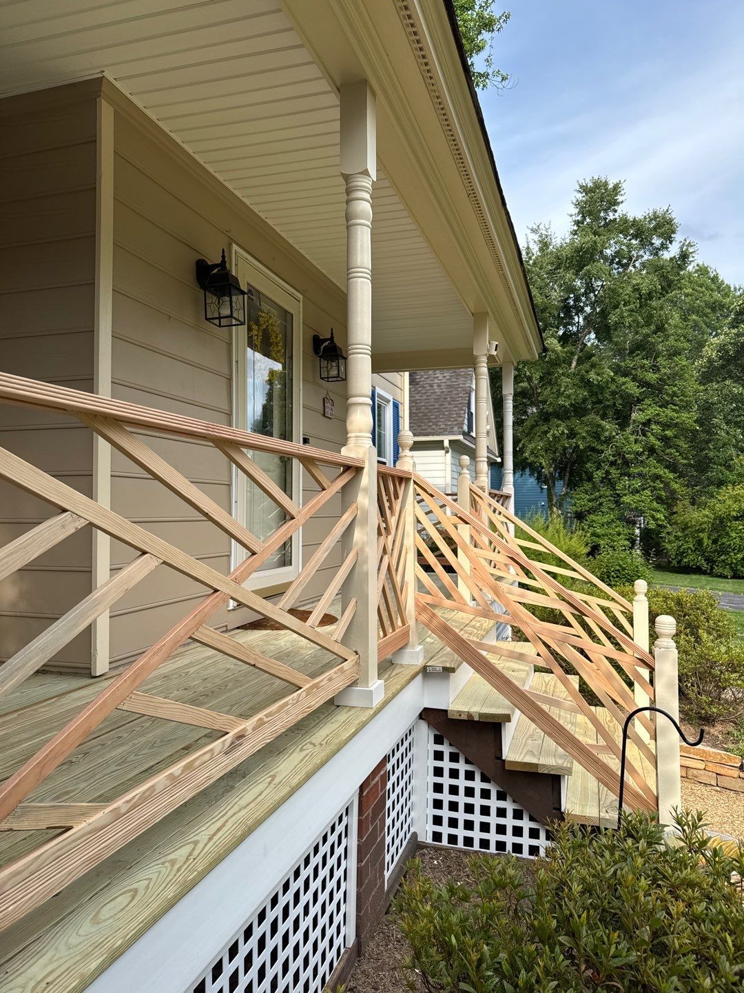 Wooden porch with lattice railing and steps. Beige siding and white trim.
