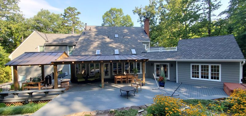 Backyard of a house with patio, pergola, and surrounded by trees.