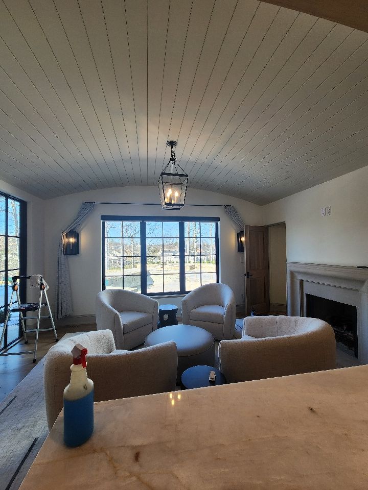 Living room with four curved cream chairs, a central coffee table, and a fireplace.
