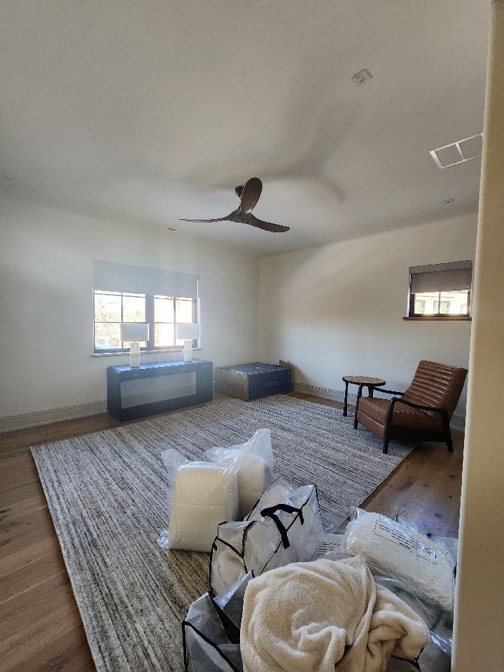 A mostly empty room with a rug, furniture, and a ceiling fan.