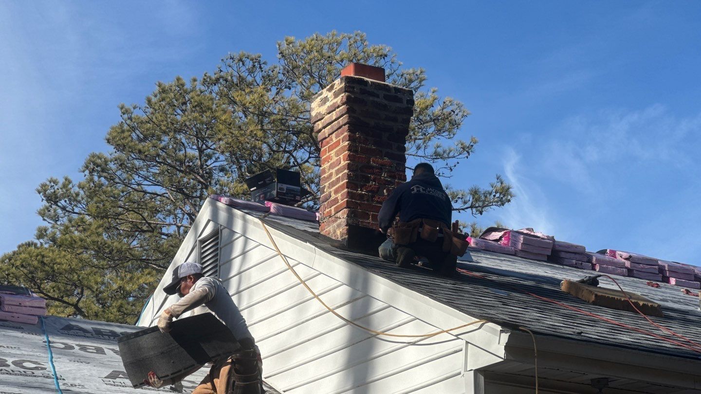 Two roofers repairing a chimney on a house roof on a sunny day.