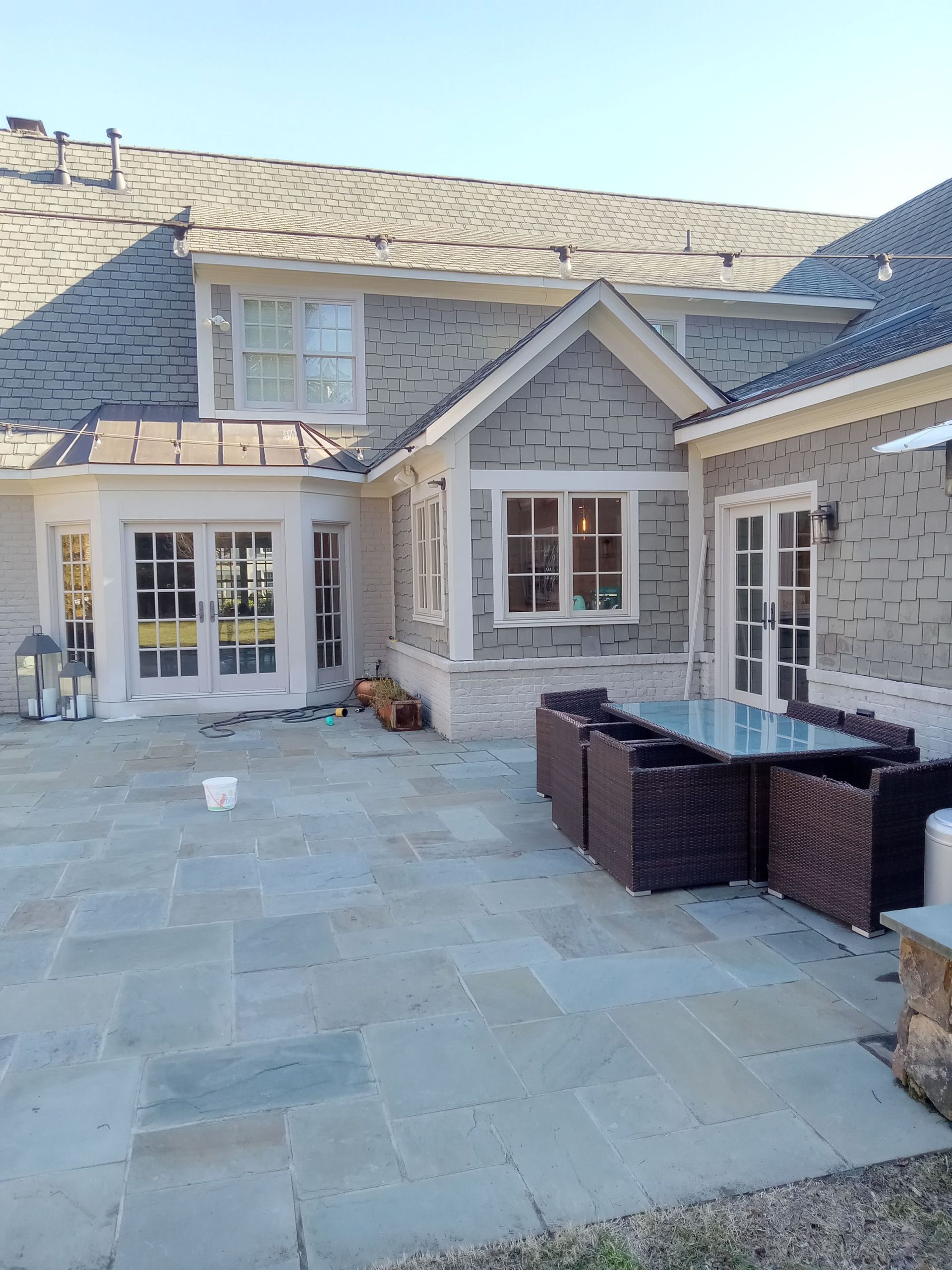 Patio with outdoor furniture next to a house with gray siding and roof.