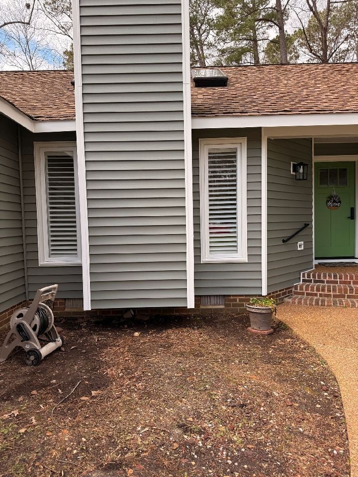 Exterior of a house with gray siding, white window trim, and a green front door.