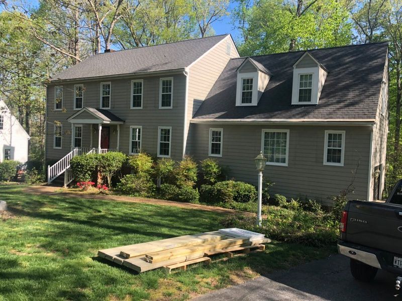 Two-story house with gray siding, gray roof, white trim, and a green lawn.