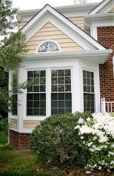 Bay window with white trim and grid pattern; beige siding and brick facade.