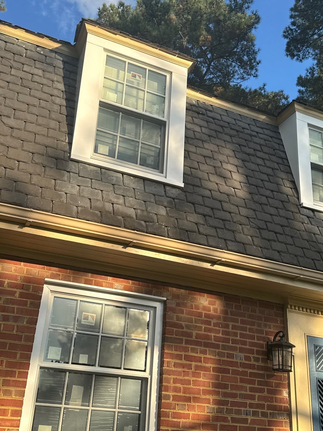 Brick building with dormer windows on a shingled roof, white trim.