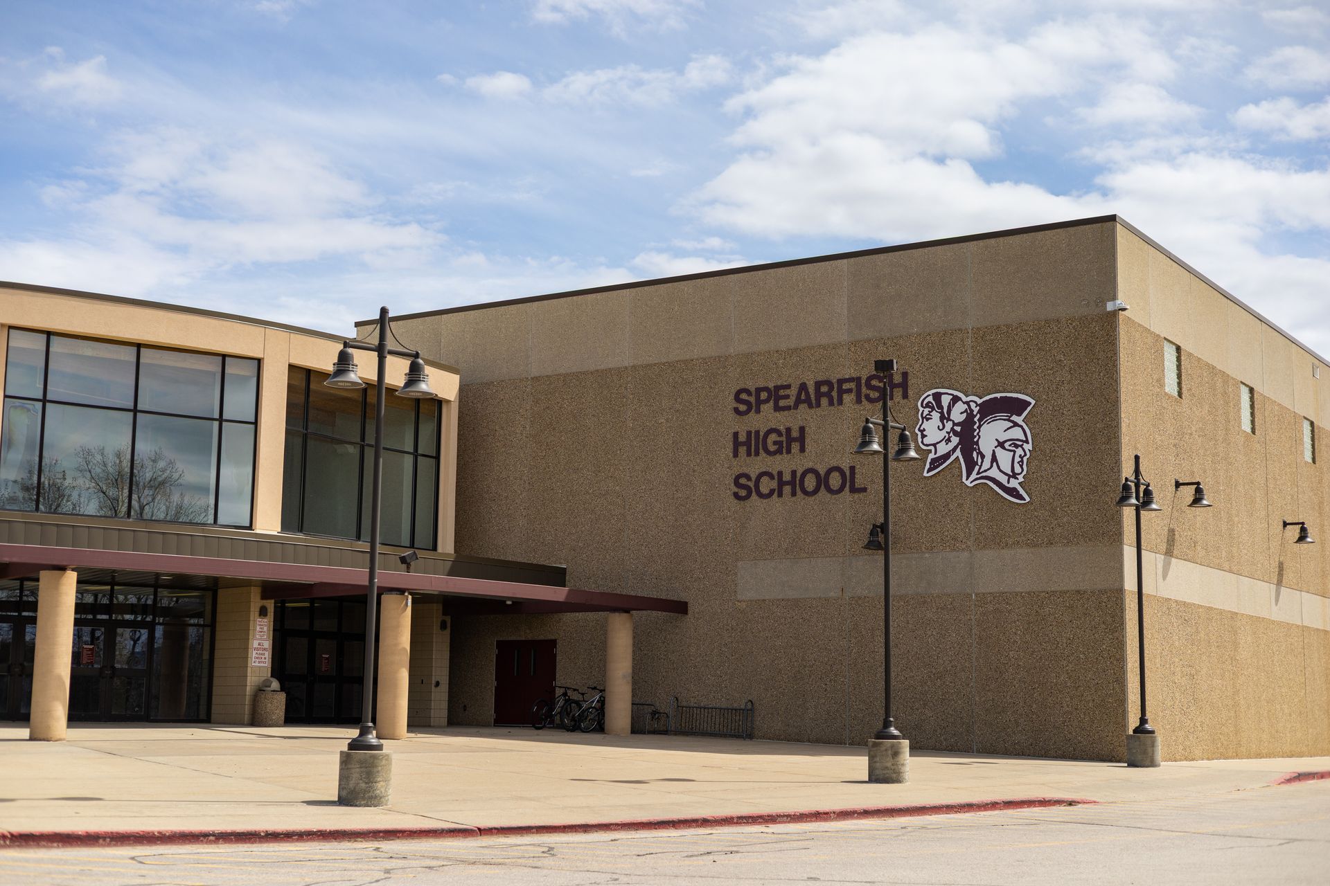 Spearfish High School exterior, beige building with sign and logo, under a cloudy sky.