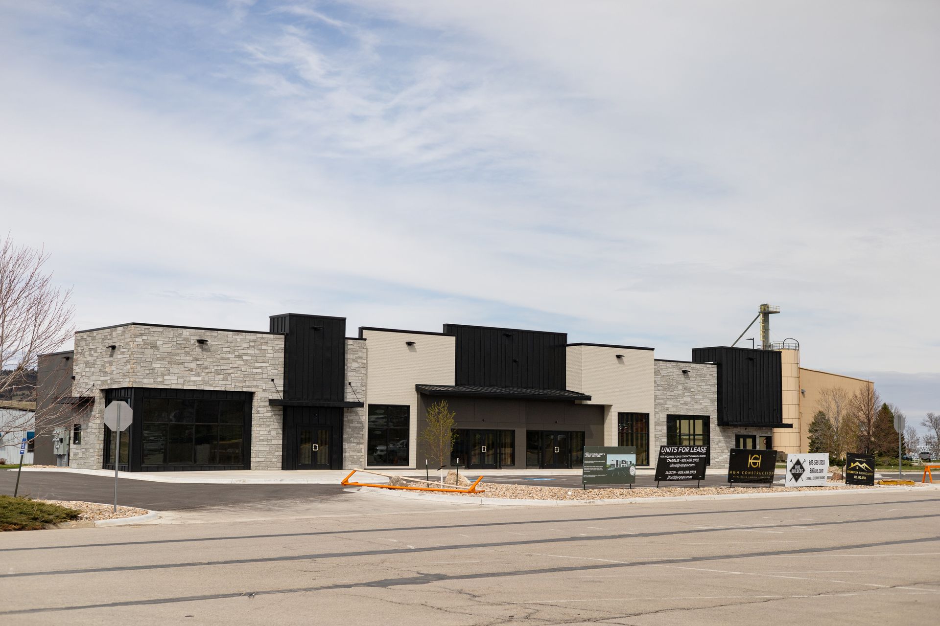 Modern building with light brick and black accents, signage on the right. Blue sky.