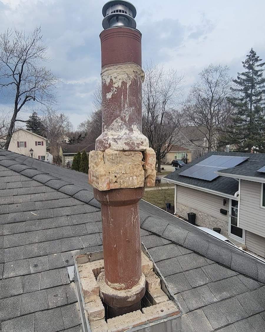 A chimney is sitting on top of a roof next to a house.