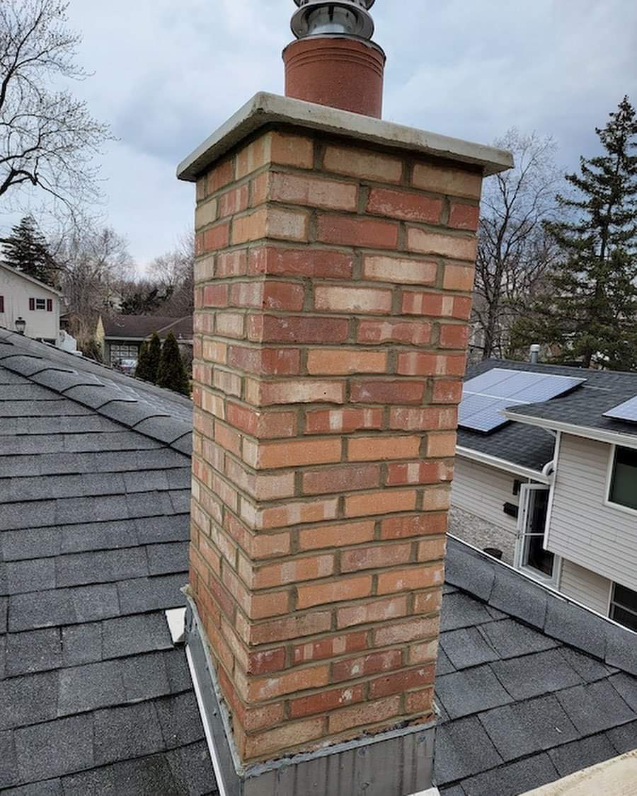 A brick chimney is sitting on top of a roof.