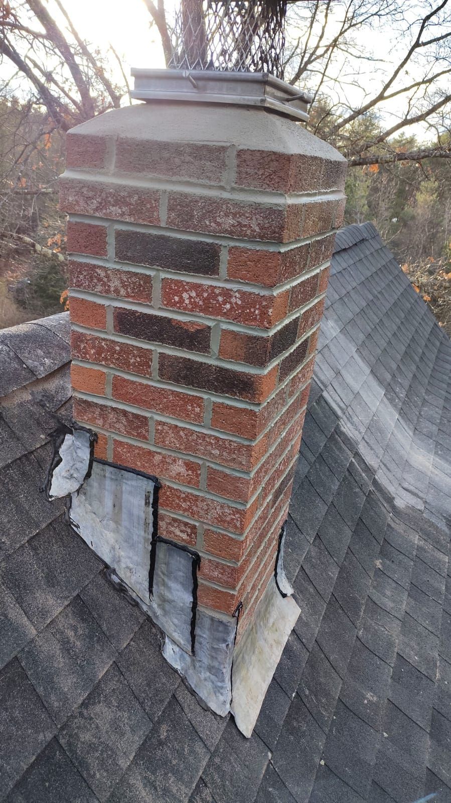 A brick chimney is sitting on top of a roof.