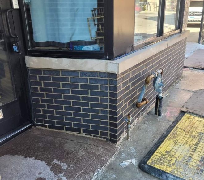 A brick building with a black door and a yellow mat in front of it.