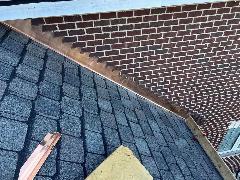A close up of a roof with a brick wall in the background.
