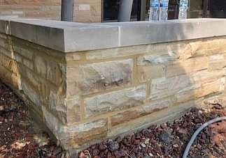 A brick wall with a concrete ledge and a hose next to it