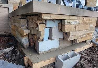 A brick wall is being built on top of a concrete base