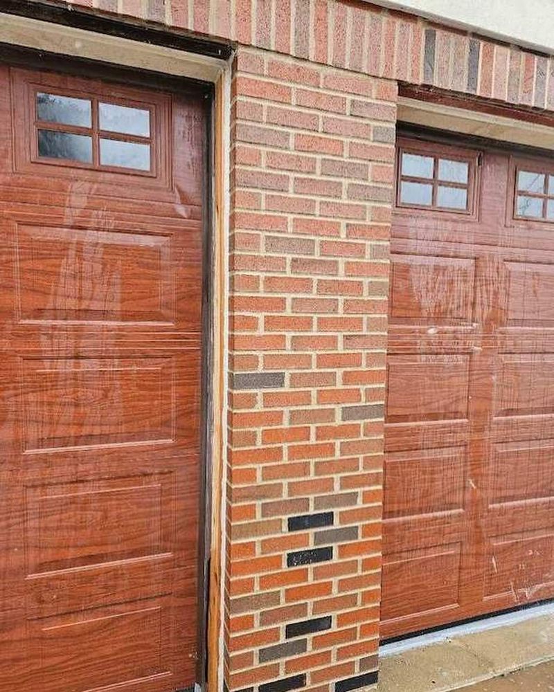 A garage door is sitting next to a brick wall