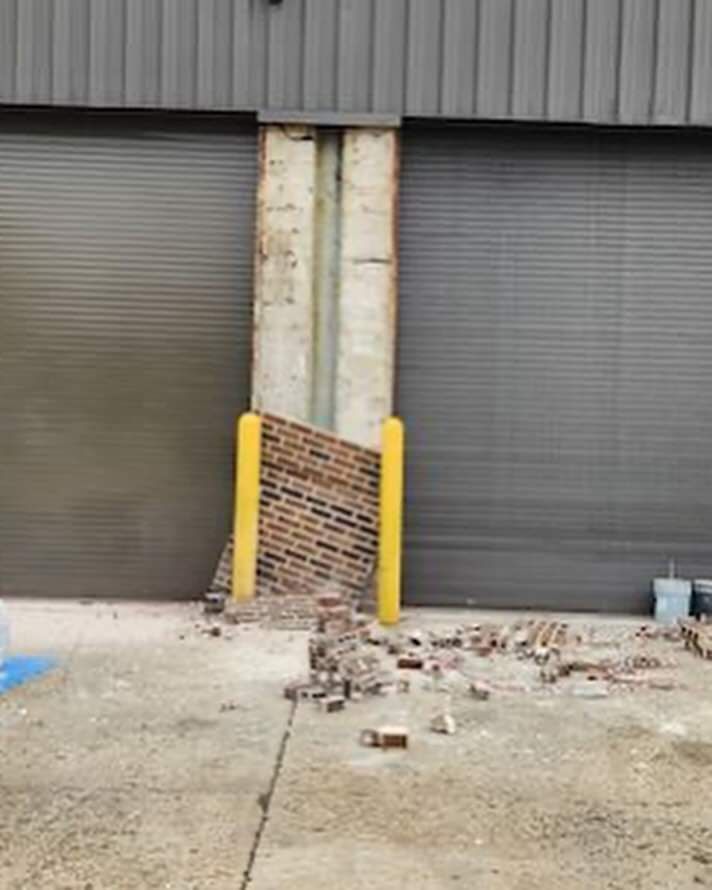 A brick wall is being demolished in front of a garage door