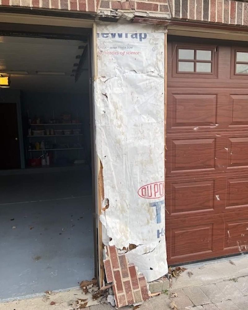 A garage door with a piece of brick missing from it