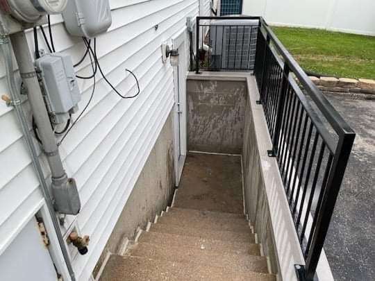 A staircase leading up to a basement with a black railing