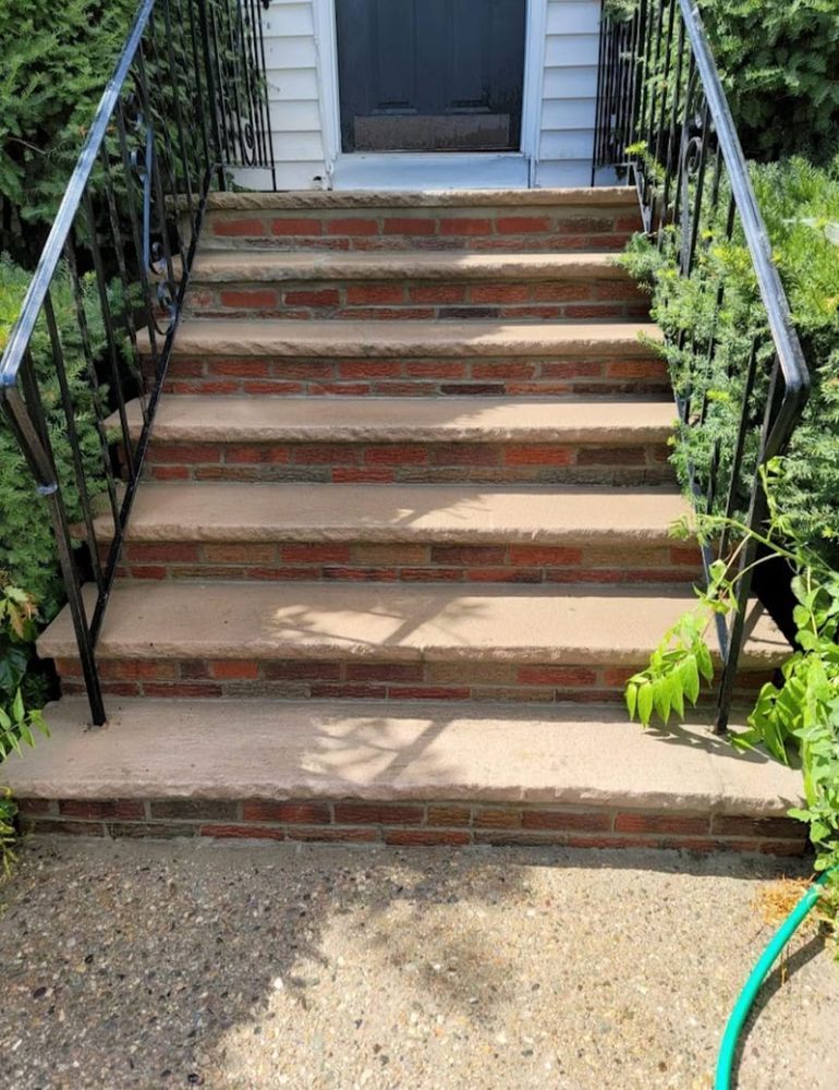 A set of stairs leading up to a house with a hose next to them.